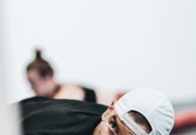 허리 통증 완화 운동법: 필라테스로 건강한 허리 만들기 man in black crew neck t-shirt wearing white cap and black framed eyeglasses