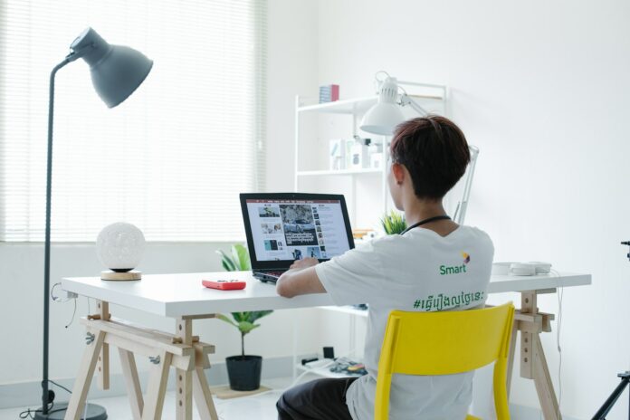Photo by SCREEN POST woman in white shirt sitting on chair using laptop computer