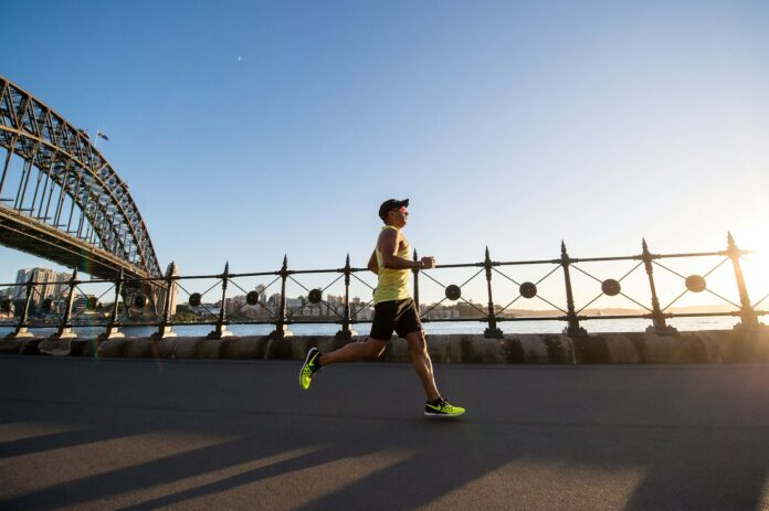 Photo by Chander R man in yellow tank top running near shore