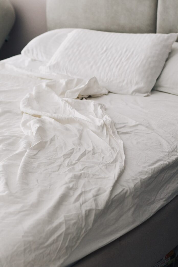 A rumpled white bed with pillows