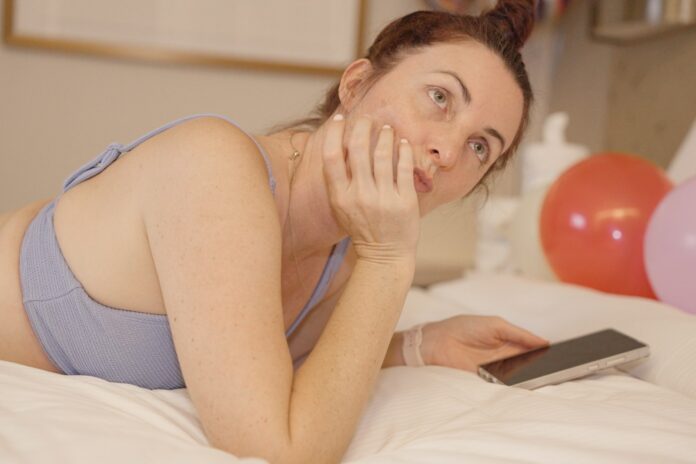 Woman lying on bed with phone and balloons