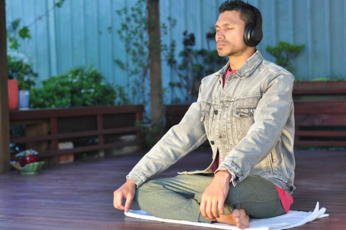Photo by Sam Bhattacharyya a man sitting on a table wearing headphones