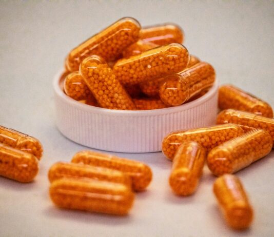 나에게 맞는 영양제, 어떻게 고를까?—최근 트렌드와 실생활 팁 Orange capsules filled with small beads spill from container.