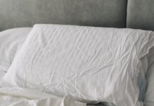수면의 질 높이는 생활 습관 변화, 실천이 답이다 A rumpled white duvet and pillows on a bed.