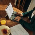 디지털 디톡스, 건강한 일상을 위한 첫걸음 Woman typing on laptop at wooden table with breakfast.